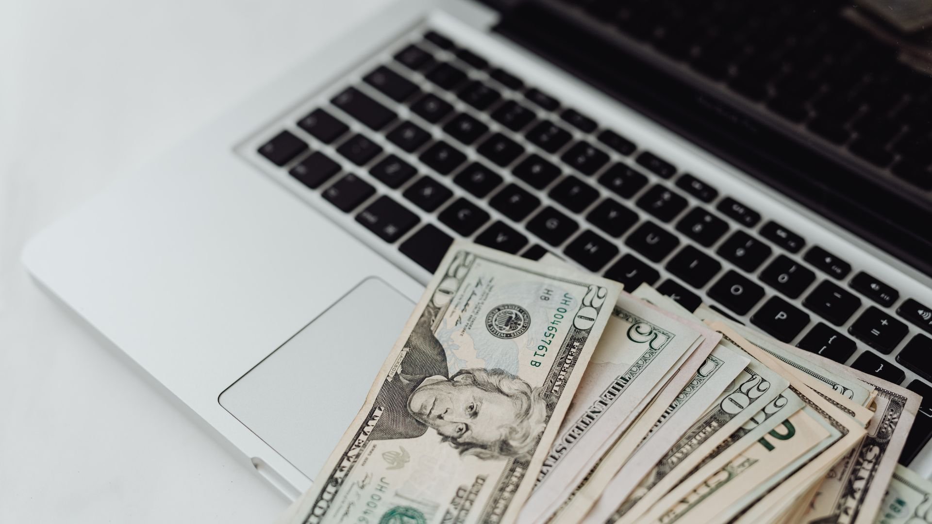 US dollar bills spread on a laptop keyboard